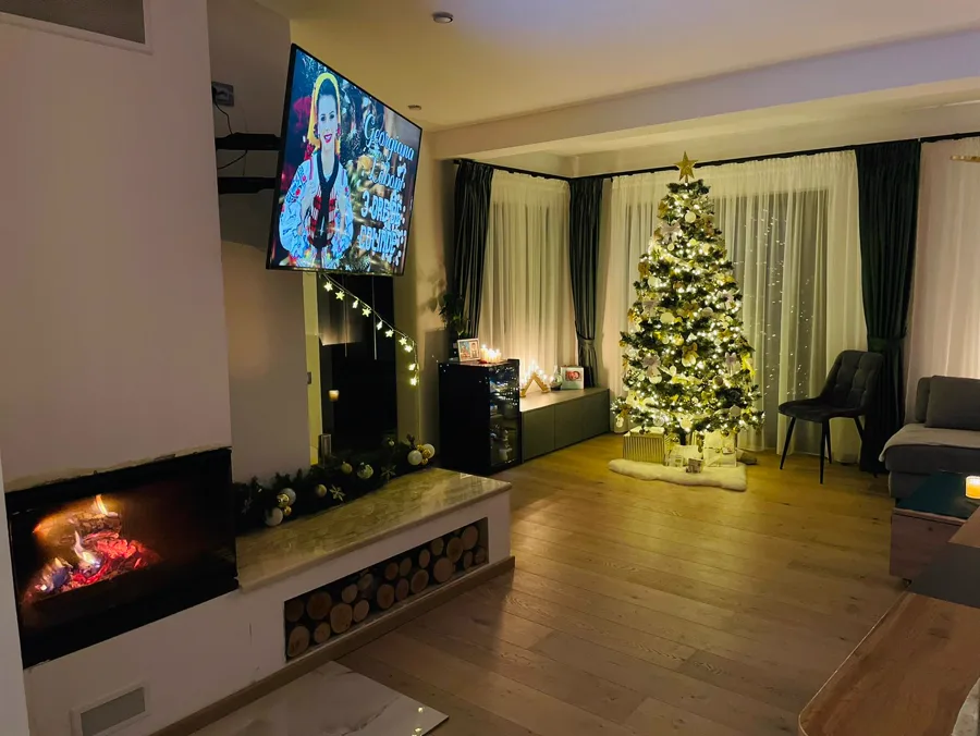 Living room decorated for Christmas with gold tree, fireplace and warm lights